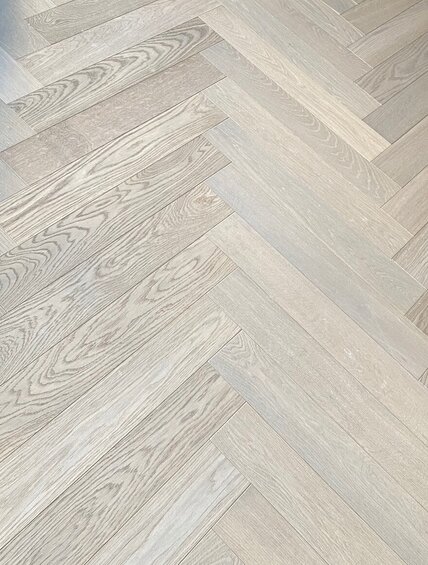 Detail bílé podlahy z kolekce Ivory a vzorem herringbone